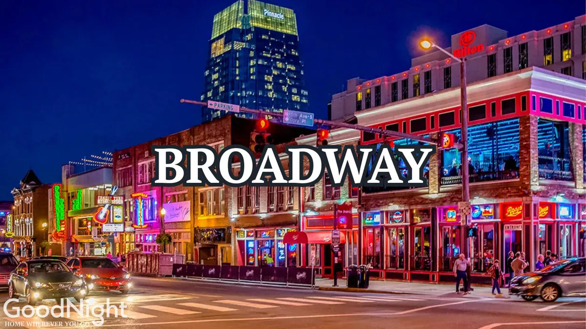 A lively street scene filled with neon signs, pedestrians, and high-rise buildings—a snapshot of Nashville’s nightlife energy. People walk between entertainment venues, restaurants, and live music spots, suggesting the excitement and vibrancy of Broadway and Music Row as night falls.